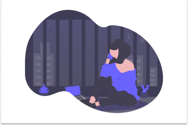 A scene showing a young woman with short dark hair at night time, she is sitting talking on the phone with her computer open in front of her